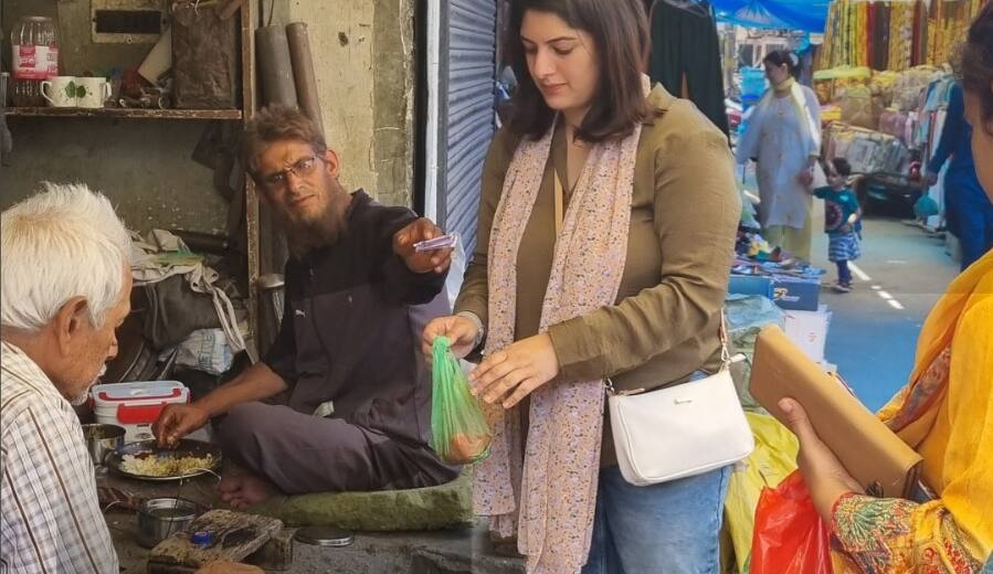 Azmat buying from a food stall in a narrow Srinagar lane