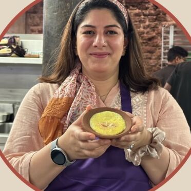 Azmat Ali Mir smiling in a kitchen, holding a small clay bowl