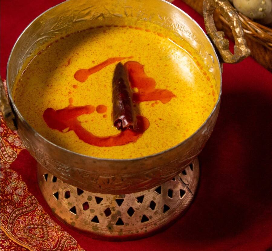 Batte dum oulv: whole potatoes in a golden gravy with a dried red chilli, in a copper bowl
